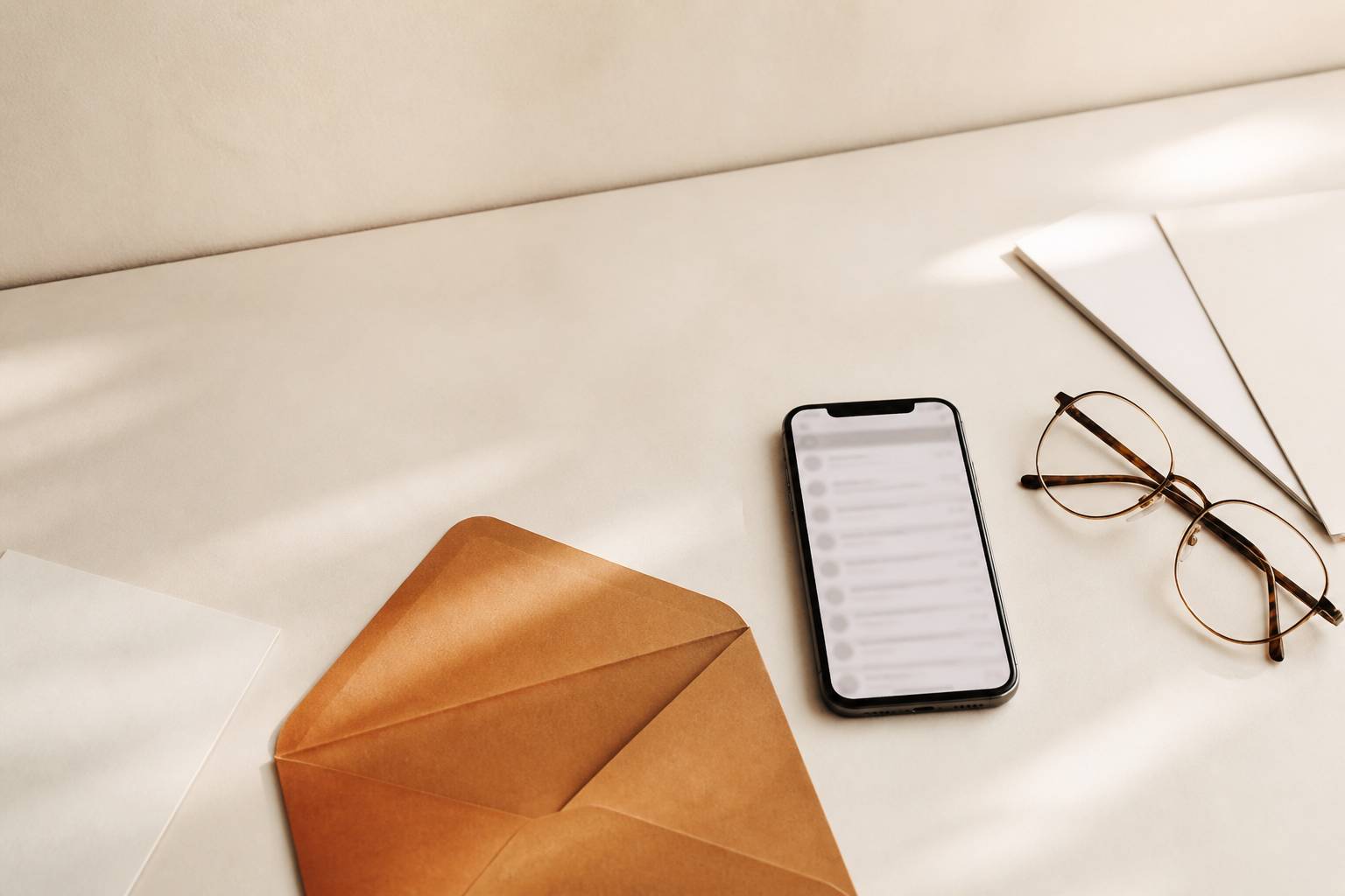 Enveloppe kraft et smartphone affichant une liste de courriels floue
