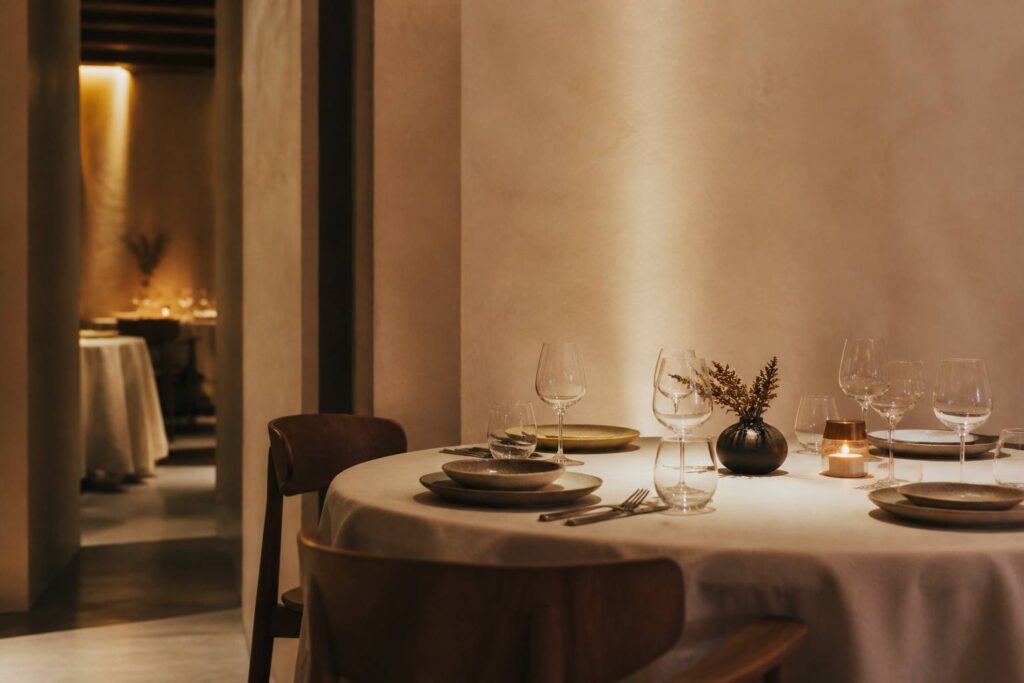 Table gastronomique intimiste dressée avec assiettes et verres